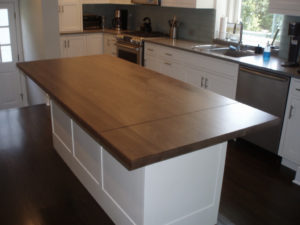 wide plank walnut island wood countertop with a hinged drop leaf and white cabinets