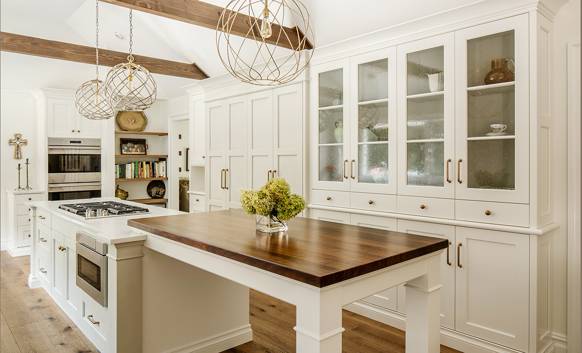 White kitchen having a walnut island countertop